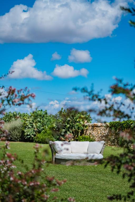a white couch sitting in the grass in a yard at Borgobianco Resort & Spa Polignano - MGallery Collection in Polignano a Mare