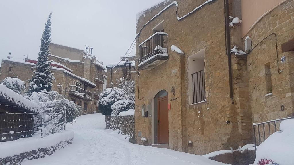 a snow covered alley with buildings and a tree at Casa Rural La Vinyeta in Ballestar