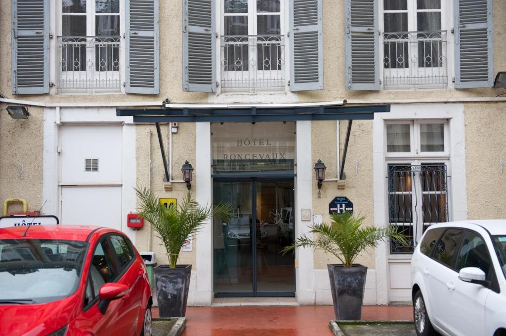 una entrada de hotel con coches estacionados frente a ella en Hôtel Le Roncevaux en Pau