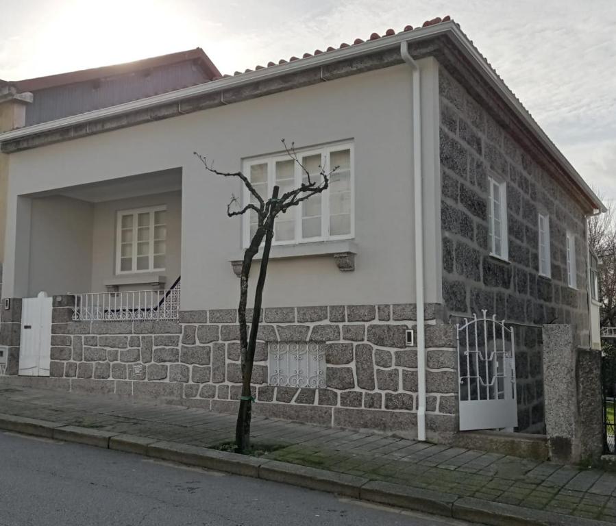 uma pequena árvore em frente a uma casa de tijolos em 4-As moradias centro em Guimarães