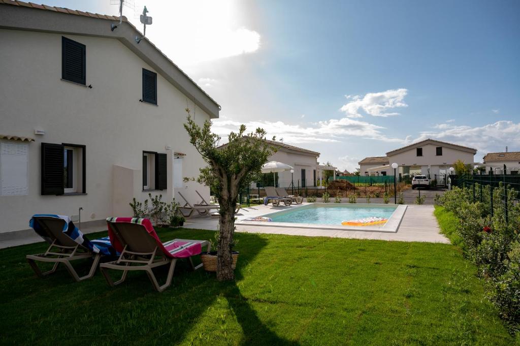 a yard with two chairs and a swimming pool at Residence Salinelle Beach Villa Salina 5 in Lascari