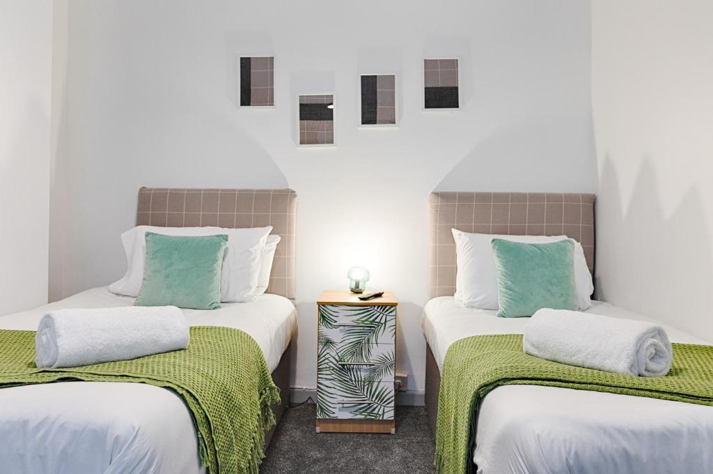 een kamer met 2 bedden met groene en witte lakens bij Pleasant Hill - TV in every Bedroom! in Swansea