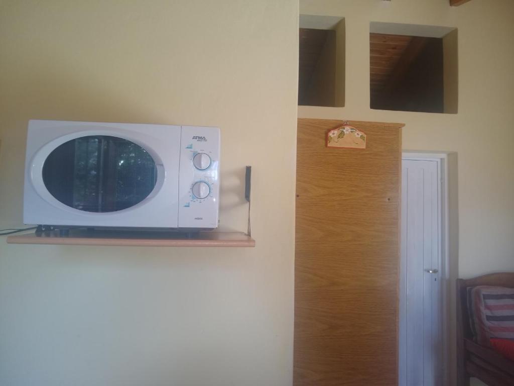 eine Mikrowelle auf einem Regal neben einer Tür in der Unterkunft Cabañas Orión in Potrerillos