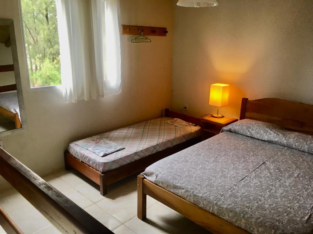 a bedroom with two beds and a lamp and a window at Villas da Jagua in Jaguaruna