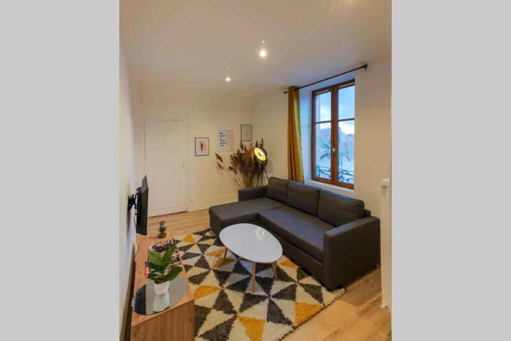 een woonkamer met een bank en een tafel bij Appart'Hôtel Le Strasbourg - RENOVÉ, CALME ET NETFLIX in Belfort