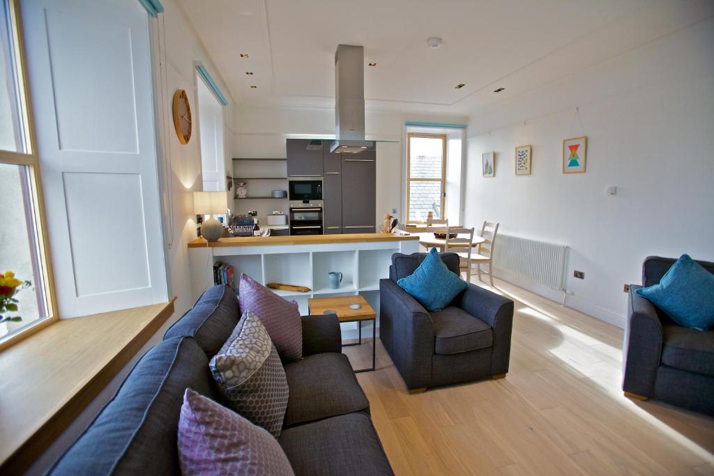a living room with a couch and chairs and a kitchen at Northlight Apartments - The Loom in Orkney