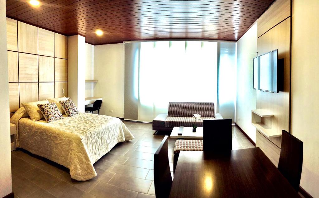 sypialnia z łóżkiem, kanapą i telewizorem w obiekcie Apartamentos Edificio San Miguel Bogotá w mieście Bogota