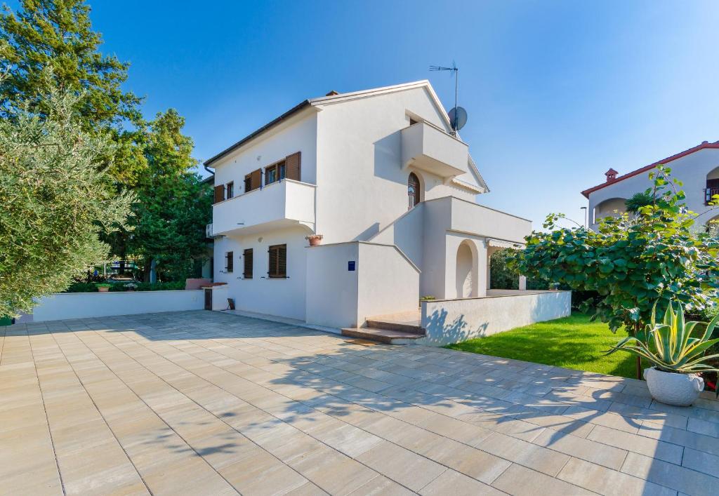 a white house with a courtyard in front of it at Apartment Marija in Poreč