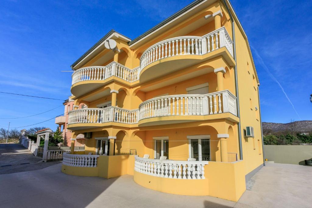 a yellow building with white balconies on it at Apartments KULAS in Novi Vinodolski