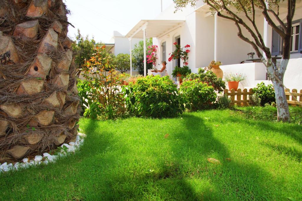 a yard with green grass and a white house at George's Place Sifnos - apartments in Apollonia