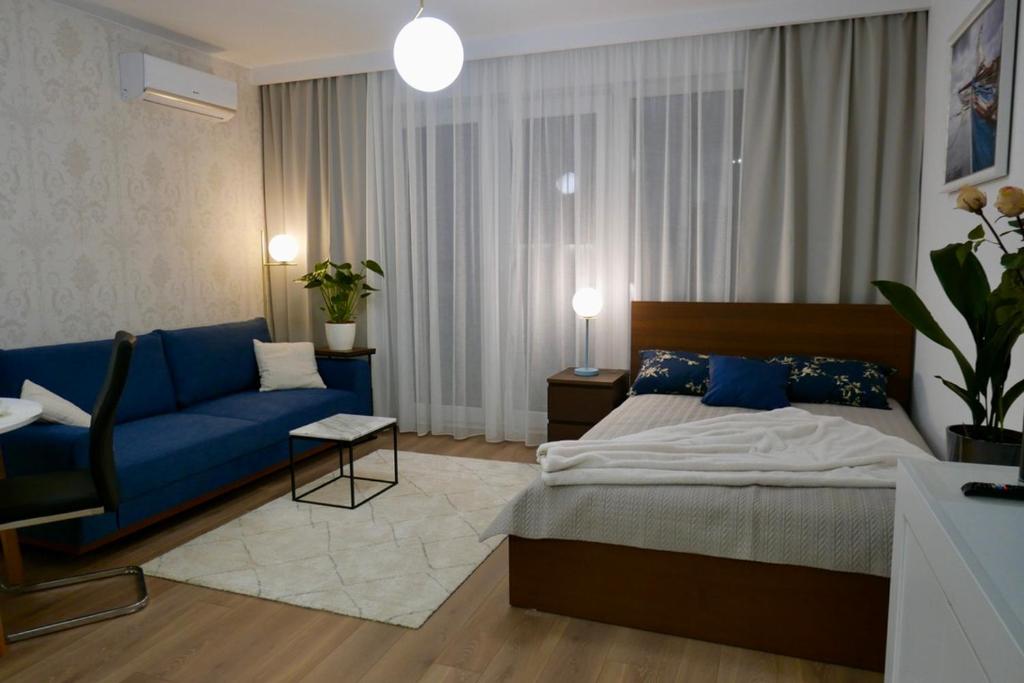 ein Schlafzimmer mit einem blauen Bett und einem blauen Sofa in der Unterkunft Studio nr 2 close to Medicover and Paley Institute in Warschau