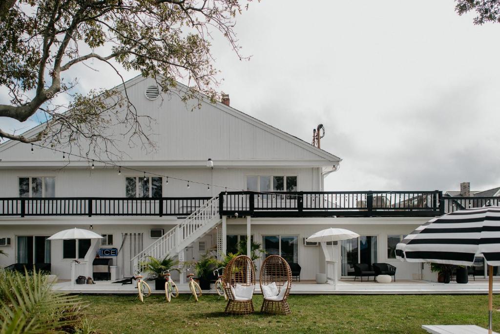 a white house with chairs and umbrellas in the yard at Aqua by American Beech - Adults Only in Aquebogue