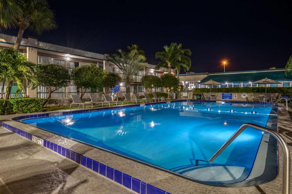 een groot zwembad 's nachts met stoelen eromheen bij Best Western Downtown Stuart in Stuart