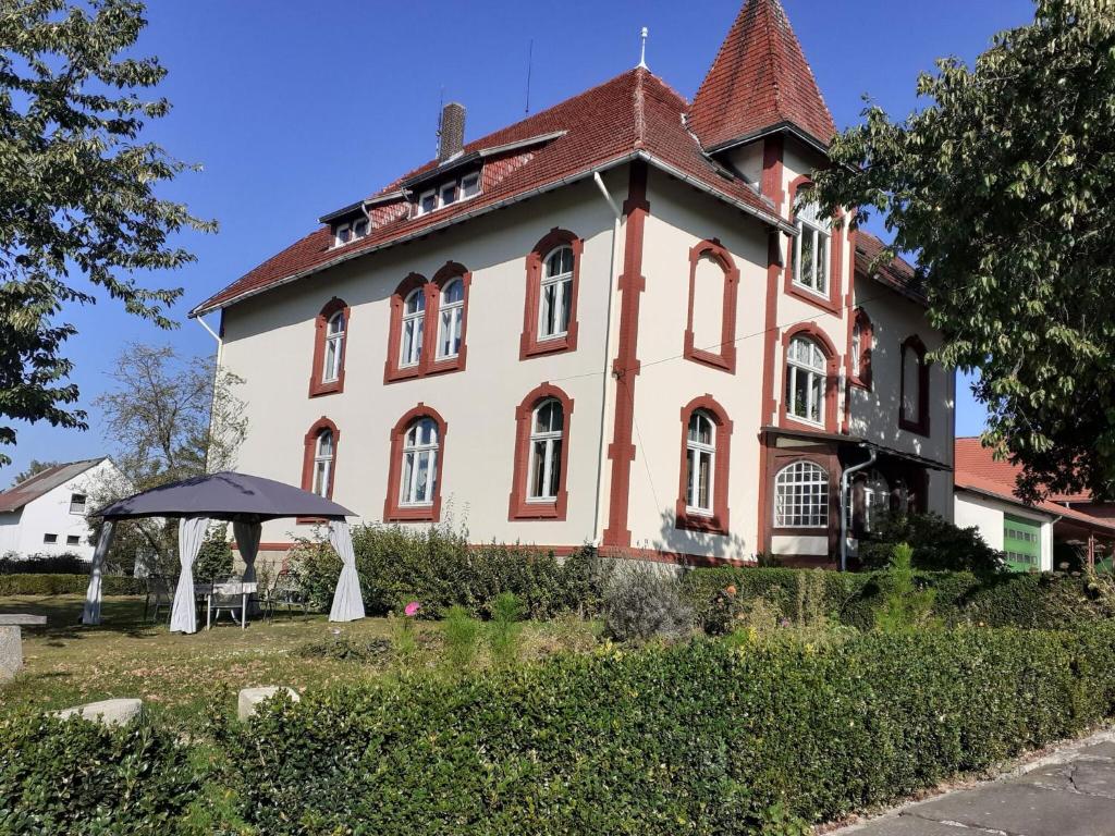 Una gran casa roja y blanca con una mesa delante. en Cosy flat on a family friendly holiday farm in northern Hesse, en Trendelburg