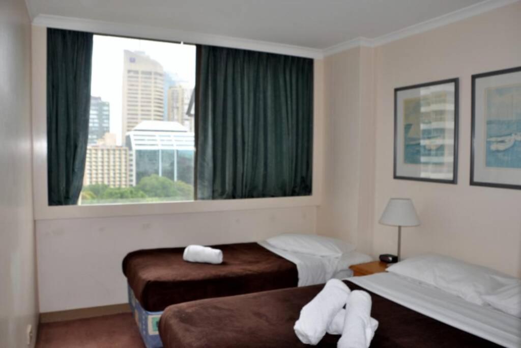 a hotel room with two beds and a window at Accommodation Sydney: Hyde Park View 2 Bedroom 1 Bathroom Pet Friendly Apartment in Sydney