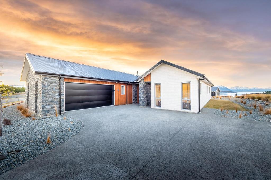 a white house with a garage in the desert at Supernova in Lake Tekapo