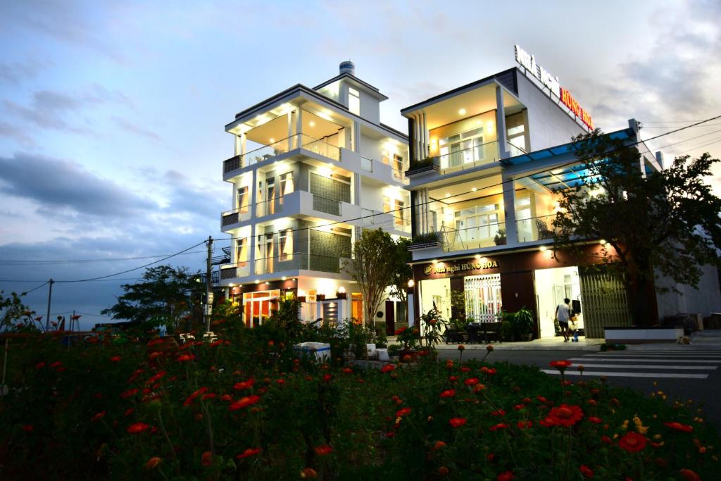 a large white building with windows and flowers in front at Nhà nghỉ Hùng Hoa in Phan Thiet