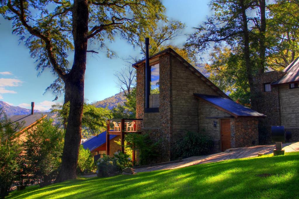 a house with a green lawn and trees at Altos del Alma Cabañas in San Martín de los Andes