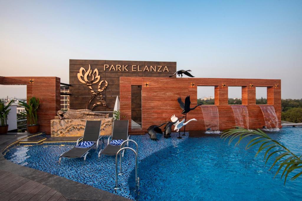 a resort with a swimming pool with chairs and a sign at Hotel Park Elanza Coimbatore in Coimbatore