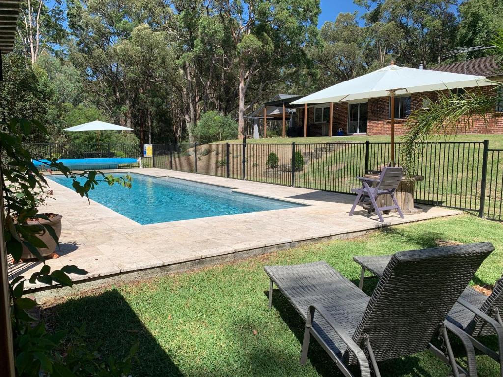 a swimming pool with two chairs and an umbrella at Studio Cottages "Bungalow" in Sydney
