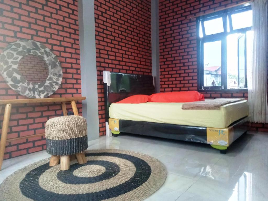 ein Schlafzimmer mit einem Bett und einer roten Backsteinwand in der Unterkunft Kurnia Homestay in Ternate
