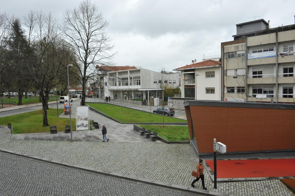 two people walking down a street in a city at Pensão Santo António in Vila Nova de Famalicão