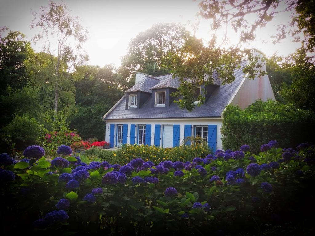 a blue house with flowers in front of it at Chambres d'hotes Chez Annie in Brélès