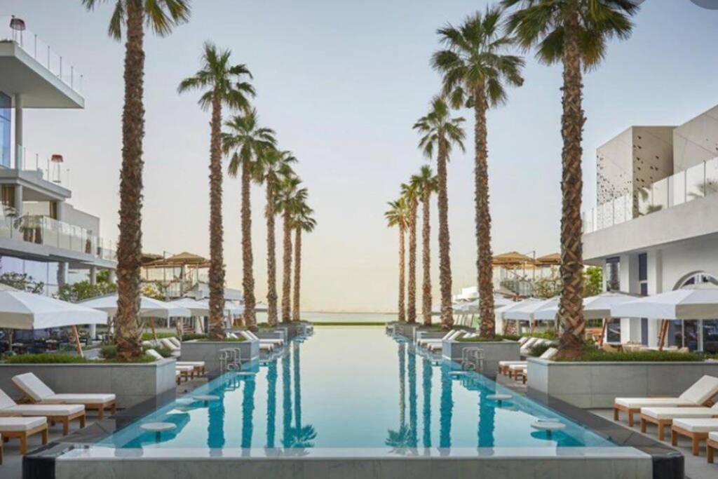 - une piscine avec des palmiers et des chaises longues dans l'établissement Five Palm Residences Dubai - 2BR Fully Furnished, à Dubaï