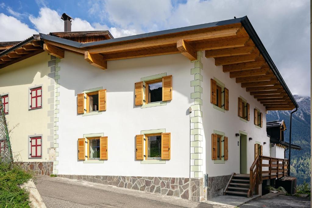 a white house with wooden windows on a mountain at La casa! in Vigo di Fassa