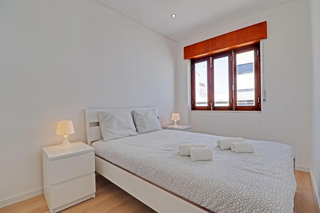 um quarto branco com uma cama e uma janela em The Fig and Almond Houses em Vila Real de Santo António