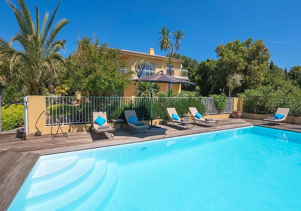 une piscine avec des chaises et une maison dans l'établissement Villa RUSCANA AVEC PISCINE PRIVÉE, à Sainte-Lucie de Porto-Vecchio