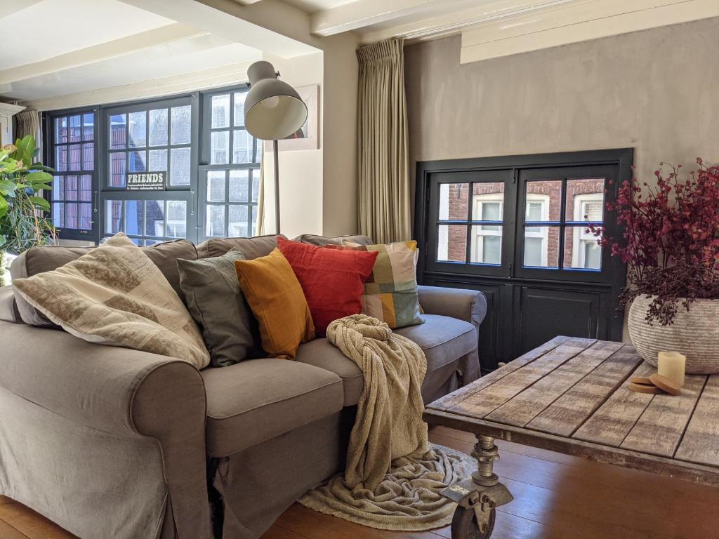 a living room with a gray couch with colorful pillows at LaneStay DamSquare in Amsterdam