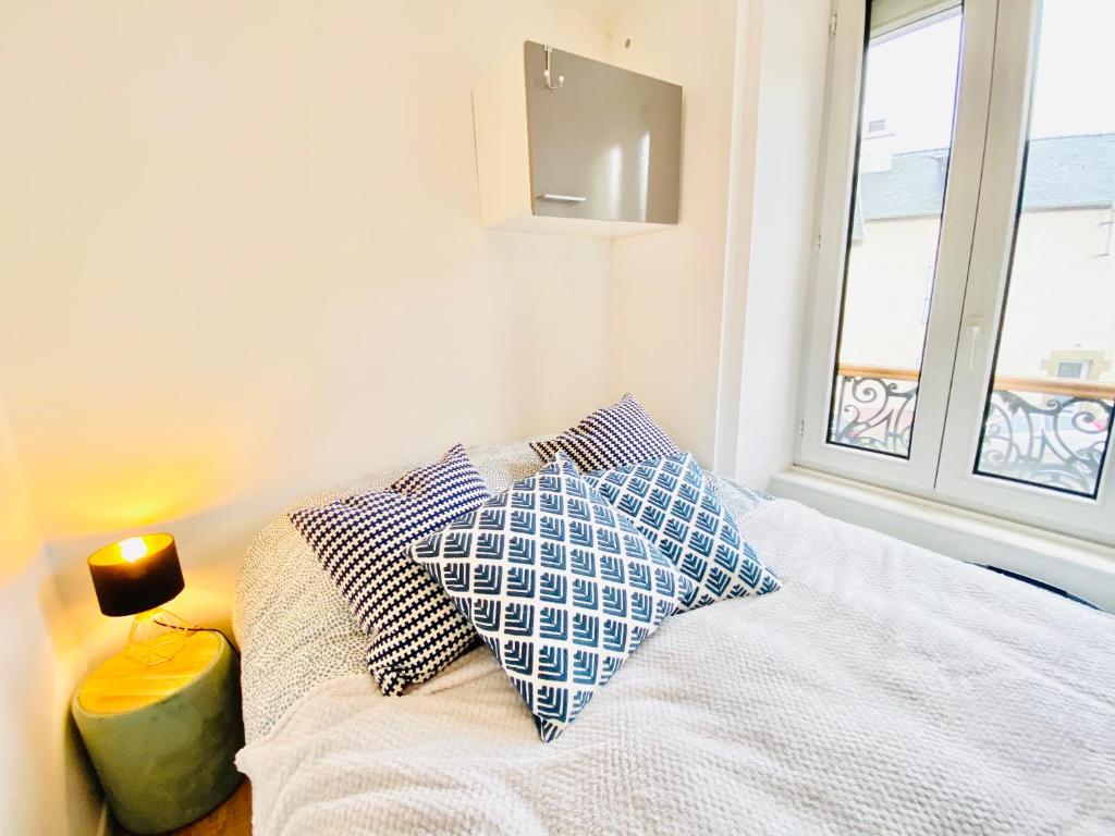 ein Schlafzimmer mit einem Bett mit Kissen und einem Fenster in der Unterkunft Studios meublés Brest Keruscun in Brest