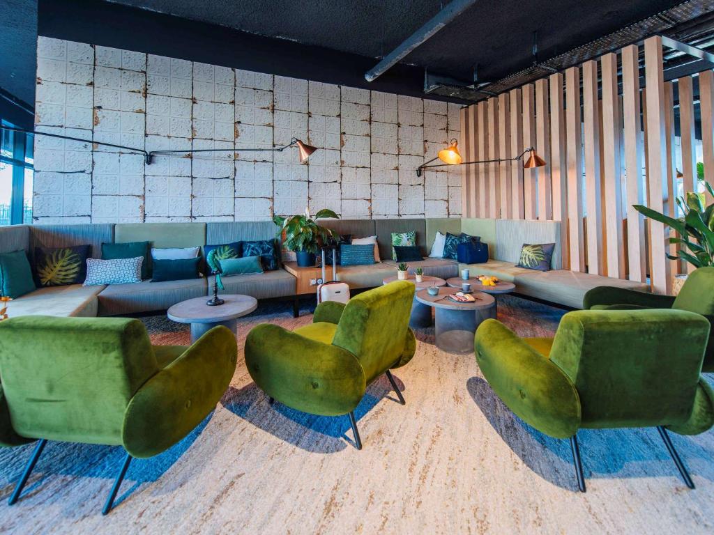 Ibis Styles Rouen Centre Rive Gauche في رووين: غرفة معيشة مع كراسي خضراء وأريكة