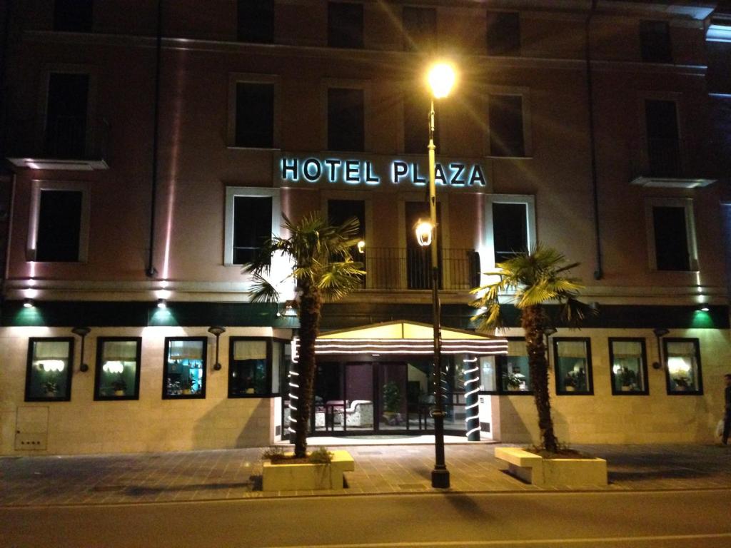 una piazza d'albergo di notte con palme di fronte di Hotel Plaza a Desenzano del Garda