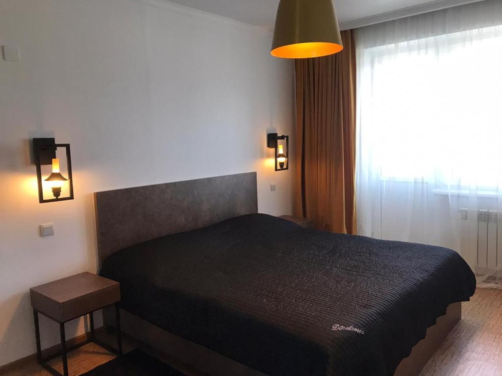 1 dormitorio con cama negra y ventana en Стильная и уютная однокомнатная квартира в г.Алматы, en Almaty