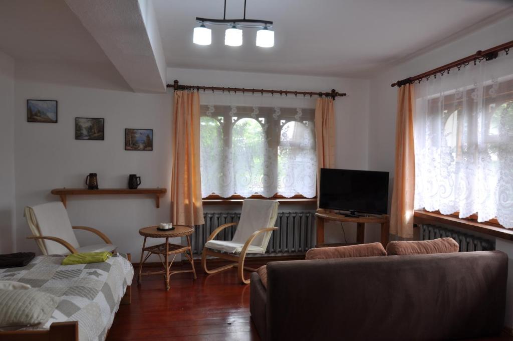 sala de estar con sofá, sillas y ventanas en APARTAMENT STELLA en Kościelisko