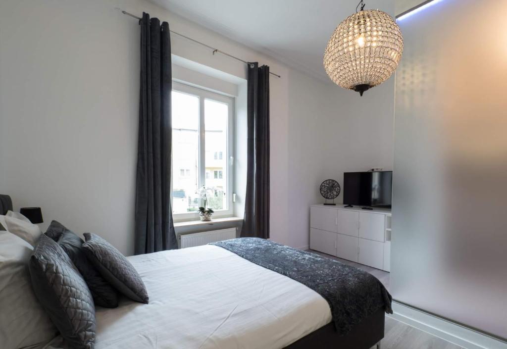 a bedroom with a bed and a television and a chandelier at EXECUTIVE DOUBLE ROOM WITH EN-SUITE in GUEST HOUSE RUE TREVIRES R3 in Luxembourg