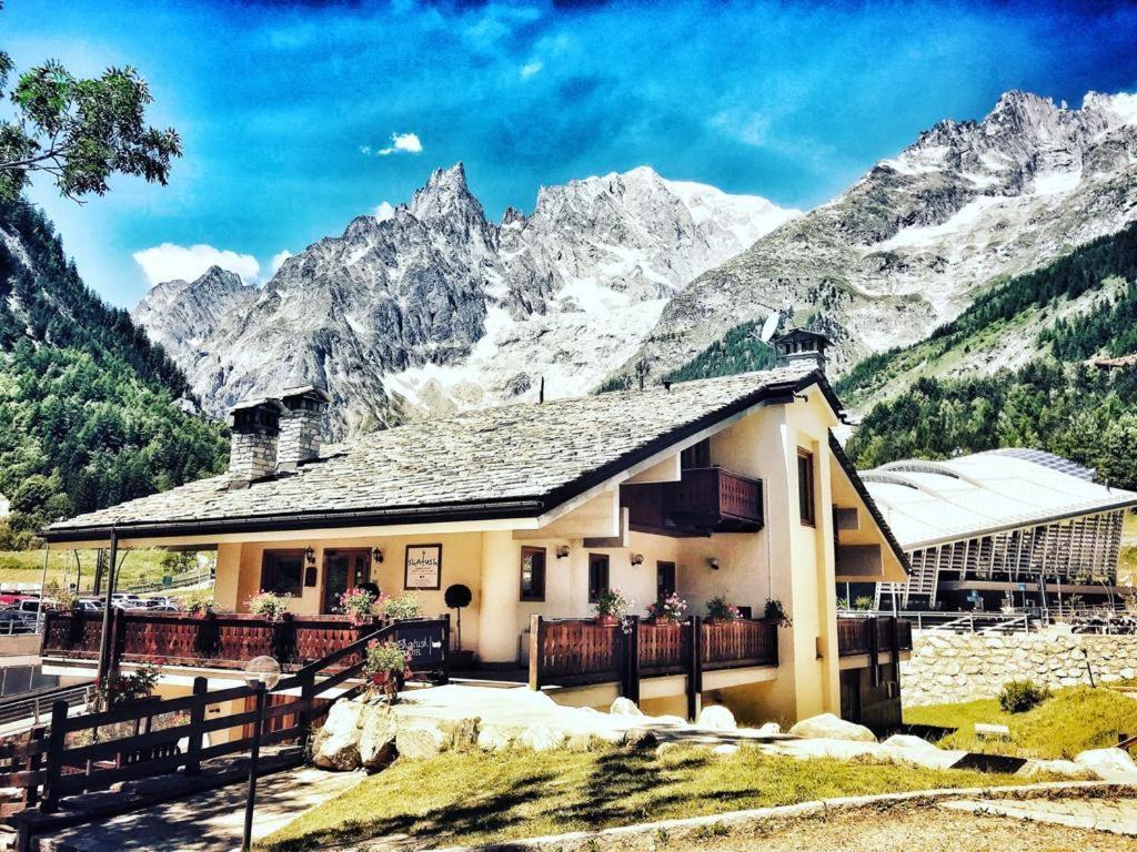 
a house with a mountain range and mountains at Shatush Hotel in Courmayeur
