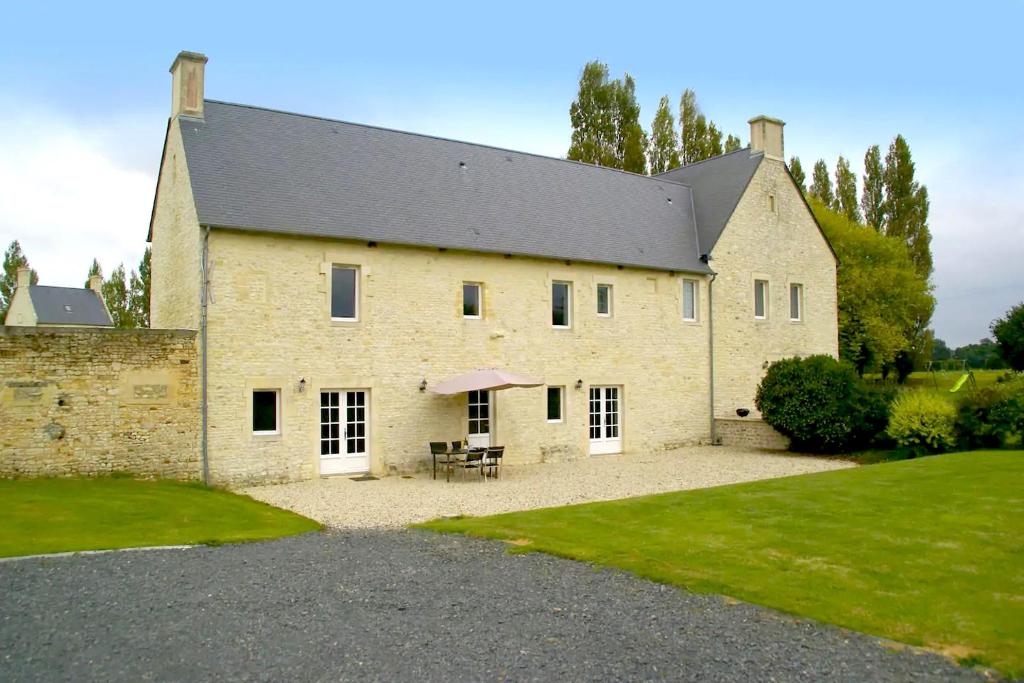 un grand bâtiment en briques avec une table et des chaises dans une cour dans l'établissement La Grange, à Maisons