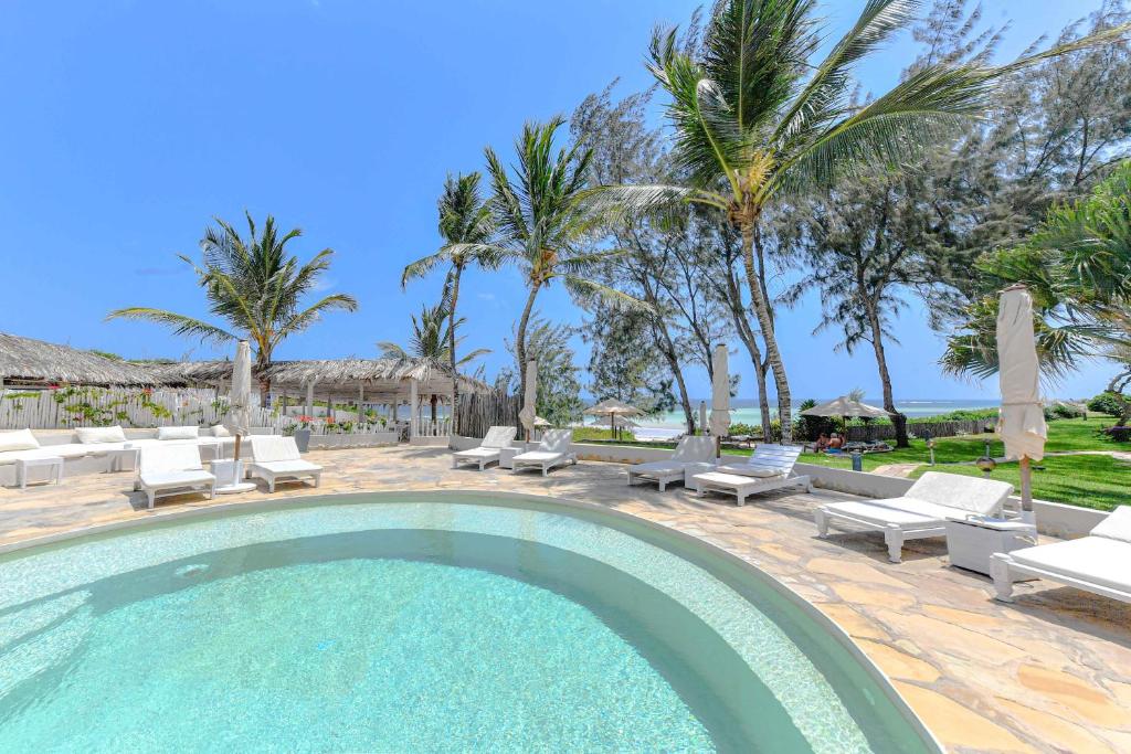 a swimming pool with lounge chairs and palm trees at Kobe Suite Resort in Watamu