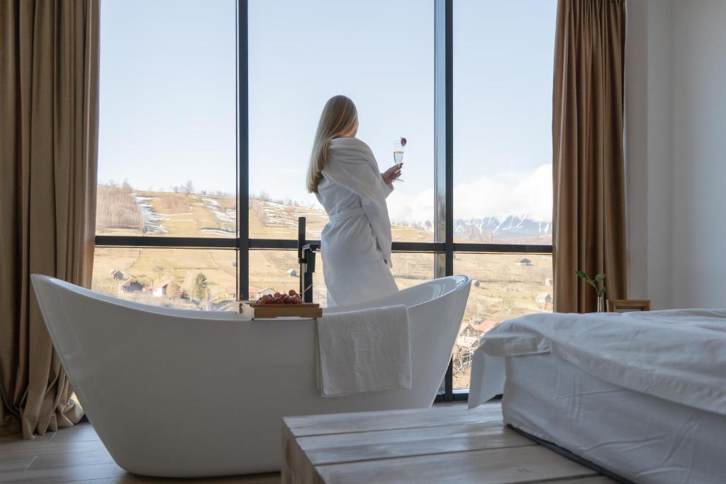 a woman standing in a tub looking out of a window at On Top Chalet in Bran