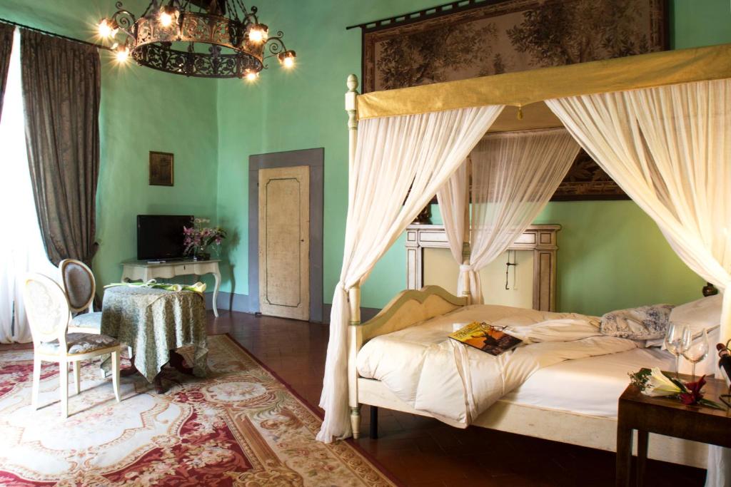 サン・カシャーノ・イン・ヴァル・ディ・ペーザにあるヴィラ イル フェディノのベッドルーム(天蓋付きベッド1台、テーブル付)