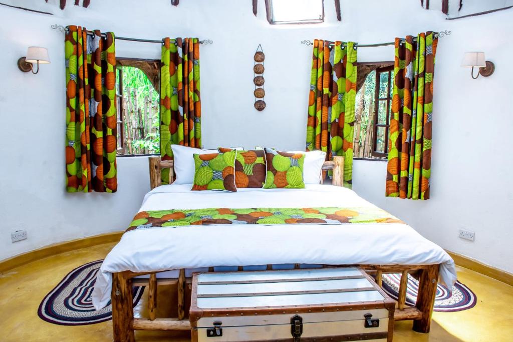 a bedroom with a bed with colorful curtains at Etana Cottage in Kakamega