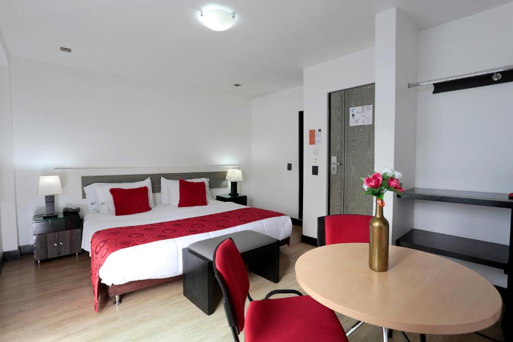 une chambre d'hôtel avec un lit, une table et des chaises dans l'établissement Hotel Bogota Expocomfort - Embajada Americana, à Bogotá