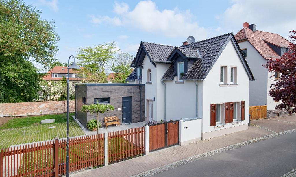 a white house with a fence on a street at Bei Meyers im Leipziger Neuseenland in Böhlen