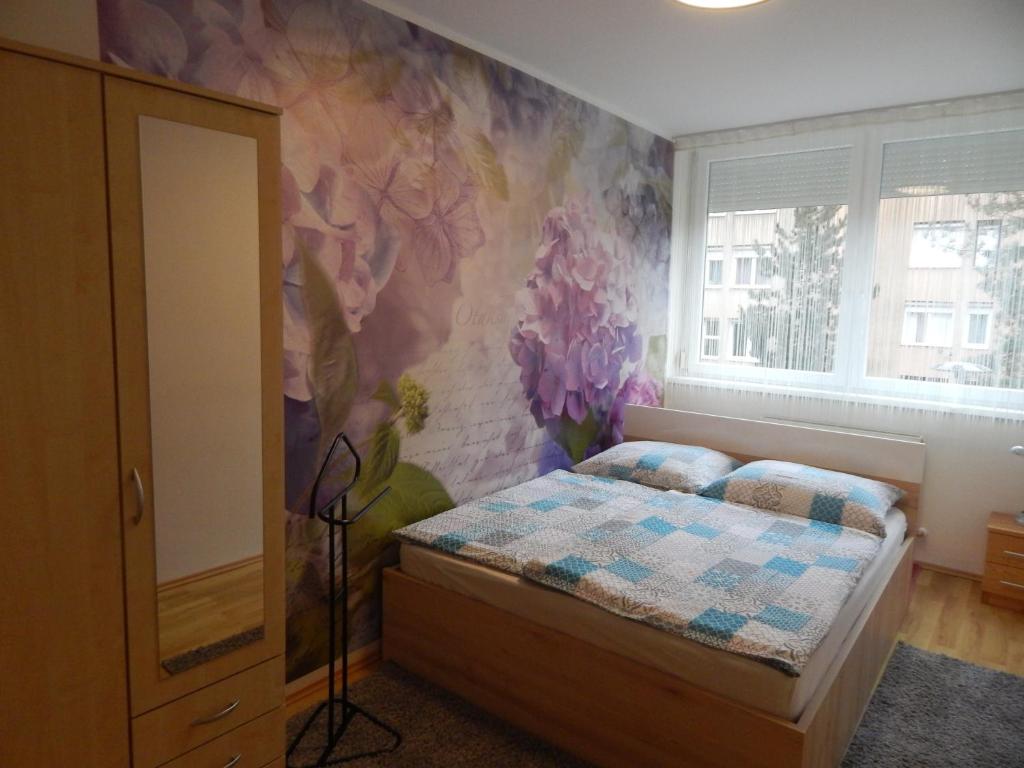 a bedroom with a bed with a flower mural on the wall at Boros Apartman in Kőszeg