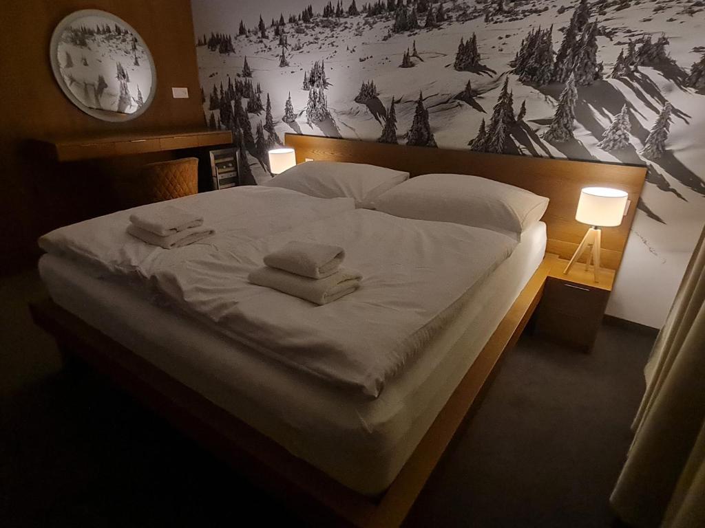 a large bed with white sheets and pillows on it at Snowland Apartmány in Valča