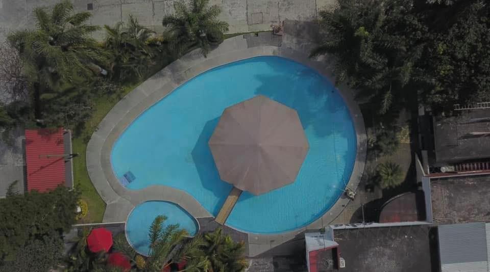 een uitzicht over een zwembad met een parasol bij Hotel D´ Alba in Río Blanco