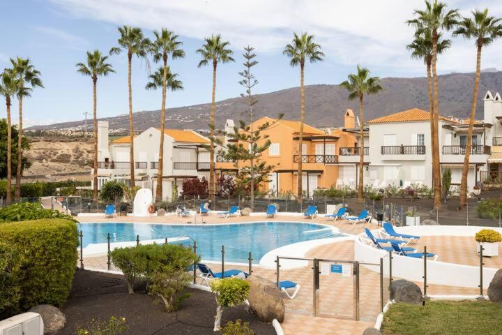 a pool with chairs and palm trees in a resort at Costa Adeje Luxury Mango in Adeje